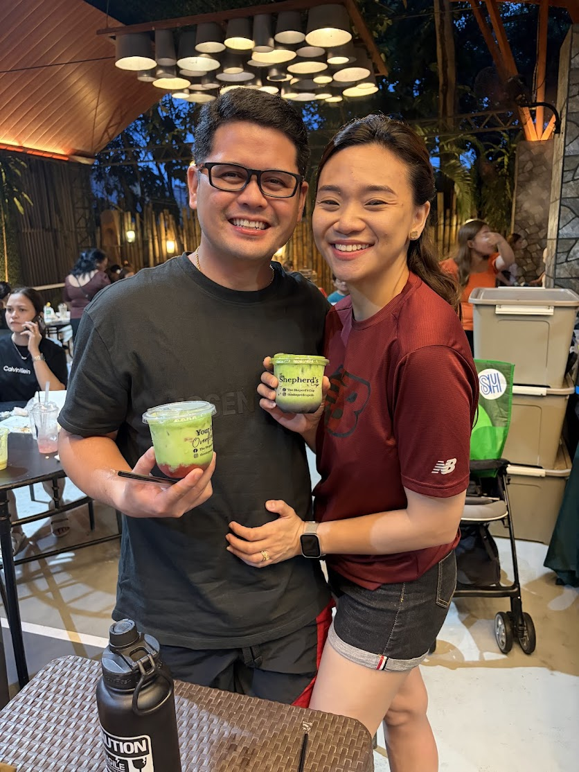 A couple smiling with Shepherd's Cup matcha drinks at the bazaar